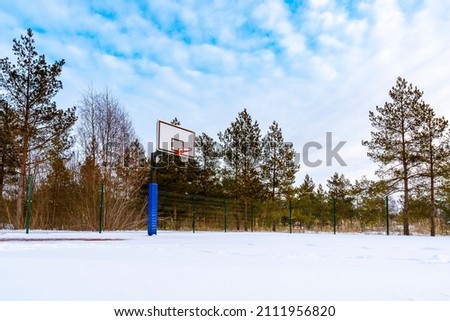 Basketball field covered with snow. Outdoor basketball court in winter season.