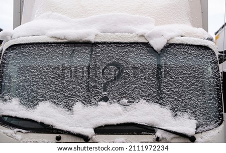 Question mark on a snowy car windshield.