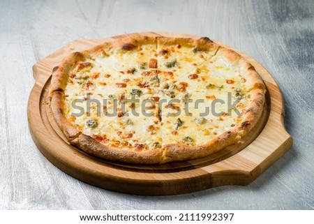 Pizza Quattro formaggi on wooden board on grey table Royalty-Free Stock Photo #2111992397