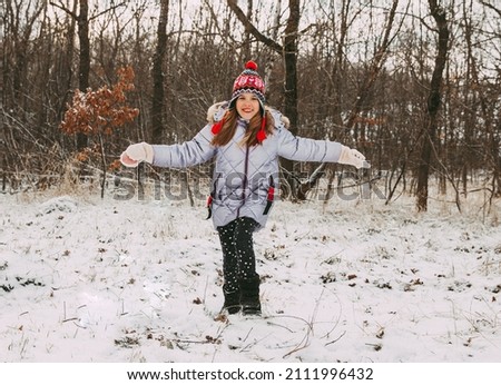 happy cheerful little girl having fun in the forest on a winter day. child plays with snow.