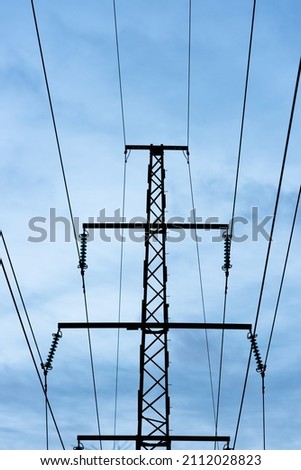 High voltage power lines against a blue cloudy sky.