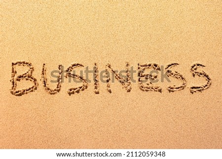 Business word written in the sand on a sunset beach