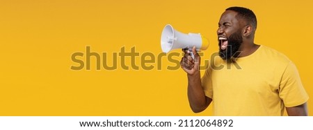 Young black man 20s wearing bright casual t-shirt hold scream shout in megaphone announces discounts sale Hurry up isolated on plain yellow color background studio portrait. People lifestyle concept Royalty-Free Stock Photo #2112064892