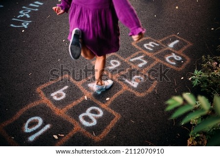 Child playing hopscotch on spray painted asphalt