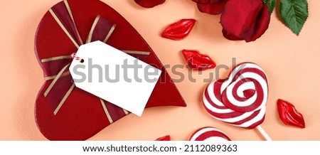Happy Valentine's Day gift with Valentine red roses, heart shape lollipops and lipstick kisses chocolates on a modern coral background. Sized to fit popular social media and web banner.