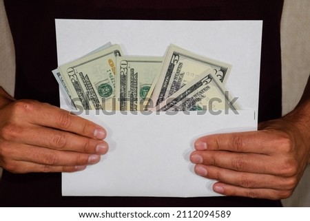 Money in a white envelope in the hands of a man. Dollars, a wad of dollars.