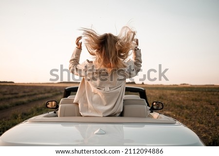 Happy woman sitting in white convertible car with beautiful view Royalty-Free Stock Photo #2112094886