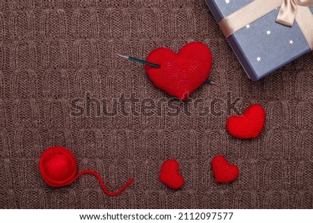 red knitted hearts and gift box on knitted background