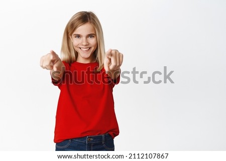 Its you. Smiling happy cute girl pointing fingers at camera, teen child congratulating, choosing or inviting you, standing over white background