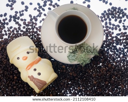 figurine of a snowman white chocolate and a cup of coffee and coffee beans.The concept of a cheerful winter morning  close-up