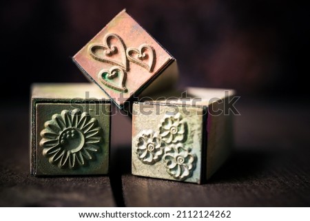 macrophotography of three vintage stamps : one with hearts and two with flowers. dark mood still life photography