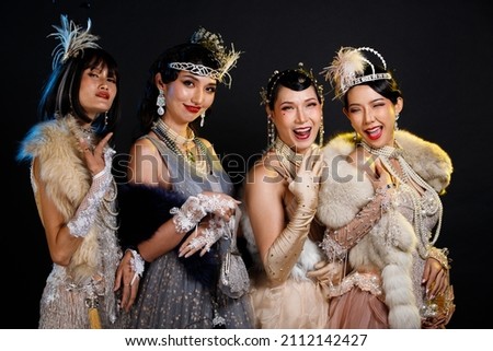 Retro vintage portrait of beautiful Gatsby woman stand look around, wait coming train for lover, feeling expression face romantic fashion style at studio black background, four group women fun Royalty-Free Stock Photo #2112142427