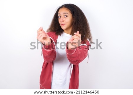 Young teen girl wearing pink jacket against white background doing money gesture with hands, asking for salary payment, millionaire business