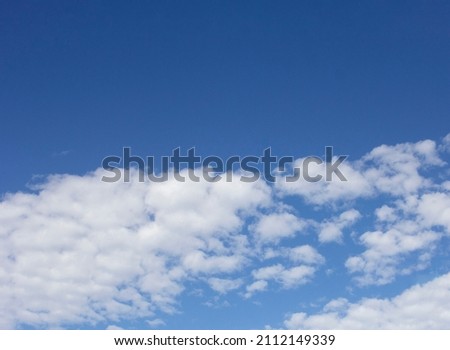 Cloudy sky with empty blue area to compose the layout. Upper part without information, lower part with white and spaced clouds. Colorful, horizontal, no people. Wallpaper, beautiful day. 