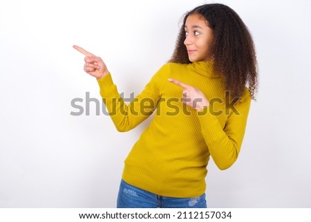 beautiful teen girl wearing yellow turtleneck sweater against white point at copyspace recommend sales discounts