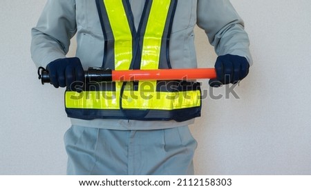 A security guard man with a red stick.