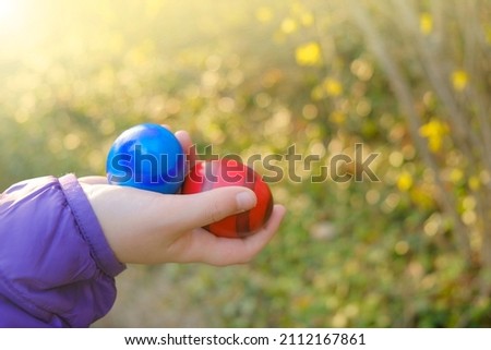 Easter Egg Hunt.Easter painted eggs in a child's hand in a blooming spring garden in the sun. Colorful easter eggs. Easter holiday tradition.