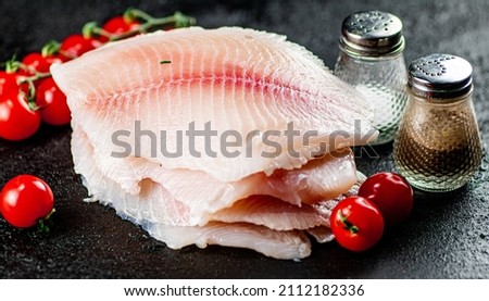 Raw fish fillet with tomatoes and spices. On a black background. High quality photo