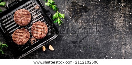 Grilled burger in a frying pan. On a black background. High quality photo