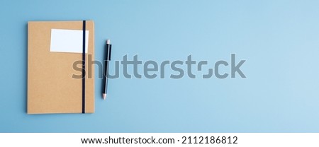 Blank white name card paper on notebook and pen on blue background, banner with copy space, moc up, template, top view, flat lay, business concept Royalty-Free Stock Photo #2112186812