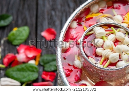 Roses, jasmine and marigolds In a large silver bowl on a wooden floor , Songkran Festival or Thai New Year Royalty-Free Stock Photo #2112195392