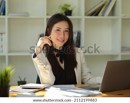 Attractive and gorgeous Asian young businesswoman or female manager sitting at her office desk in the modern office room. Royalty-Free Stock Photo #2112199883