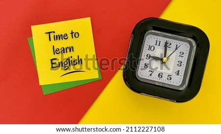 Time to learn English - message on yellow notepad. With alarm clock, red and yellow background. Business concept.