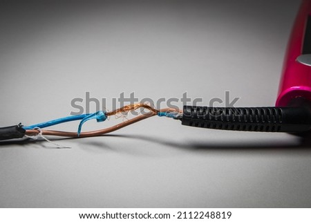 Broken power cord for home electrical appliances. Mechanically damaged electrical cable. Royalty-Free Stock Photo #2112248819