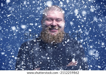 A handsome brutal man with a beard smiles and laughs. Snowfall. Romantic