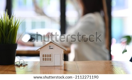 Small house model, keys and houseplant on wooden table. Real estate investment concept.