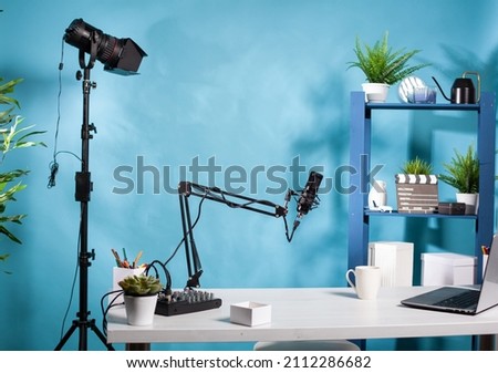 Professional video light stand in empty vlog broadcasting studio with microphone used for recording social media content. Vlogging setup with digital mixer console and laptop computer.