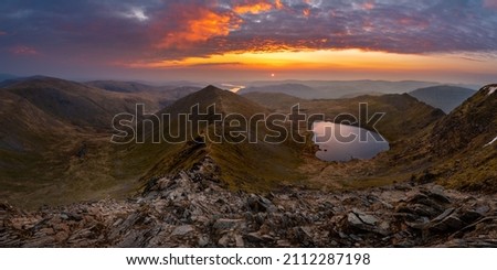 Beautiful vibrant sunrise overlooking Red Tarn and Ullswater from the summit of Helvellyn mountain range. Wide panoramic Lake District views. Royalty-Free Stock Photo #2112287198