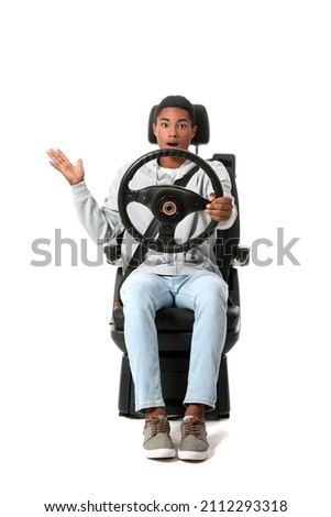 Stressed African-American man in car seat and with steering wheel on white background Royalty-Free Stock Photo #2112293318