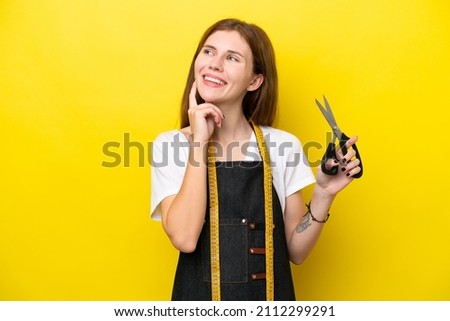 Young seamstress English woman isolated on yellow background thinking an idea while looking up Royalty-Free Stock Photo #2112299291