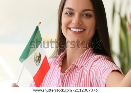 Beautiful young woman with flag of Mexico at home