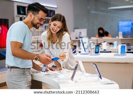 Shopping a new digital device. Happy couple buying a smartphone in store.