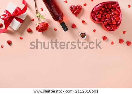 Valentine's day frame with romantic gift, rose flower, red wine, hearts chocolate sweets on pink background. View from above. Space for your greetings.