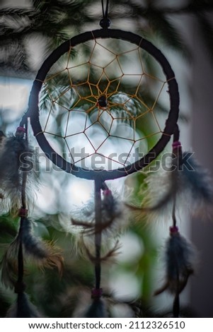 Dream catcher with feathers threads and beads rope hanging and nice bokeh background - art picture with depht of focus