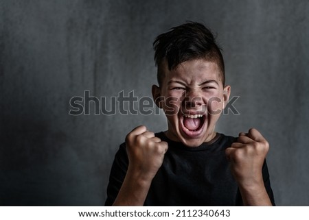 Teen boy screaming in anger on dark background. The problem of helping teenagers in a difficult period  Royalty-Free Stock Photo #2112340643