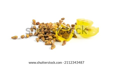 Grape oil seed in small vintage bottle isolated on white background. Heap of grape seeds with green slices and cold press organic essential oil, tincture, extract, infusion