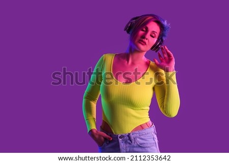 Beautiful woman with unusual hair listening to music on color background