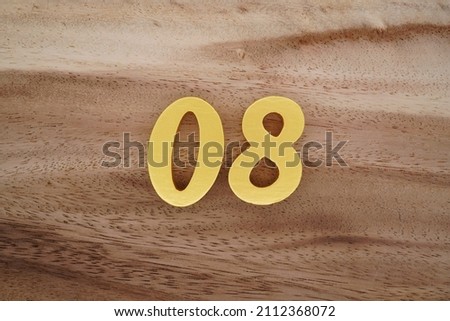 Wooden Arabic numerals 08 painted in gold on a dark brown and white patterned plank background.