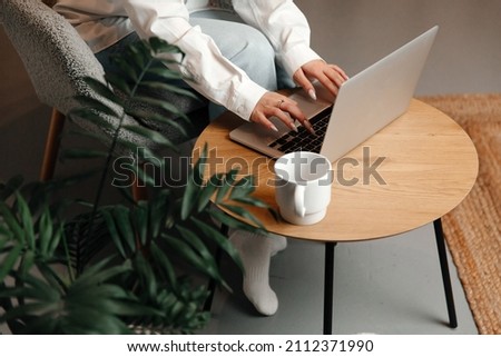 The picture shows morning routine. The girl is working on her laptop and drinking tea