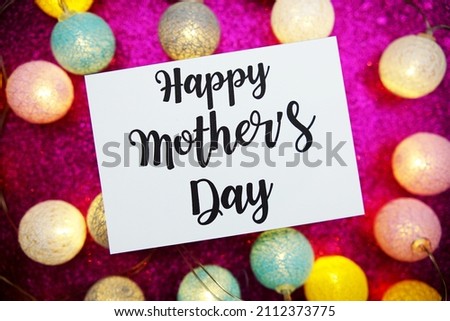 Happy Mother's Day text on paper card with LED cotton balls decorate on pink background