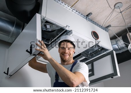 smiling hvac technician at work. ventilation, heating system maintenance and repair Royalty-Free Stock Photo #2112391724
