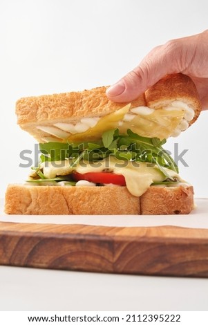 Person removing toast off sandwich with vegetables
