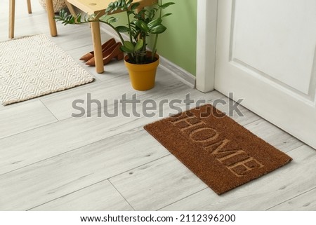 Brown door mat on floor in hallway Royalty-Free Stock Photo #2112396200
