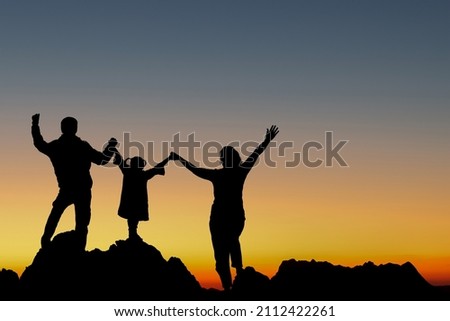 Silhouette happy family raised hands enjoying sunset on top mountain.