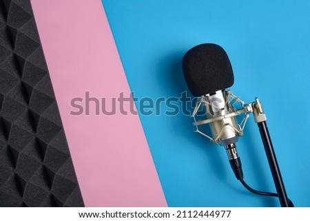 Flat lay of microphone and acoustic foam panel, ober pink and blue background