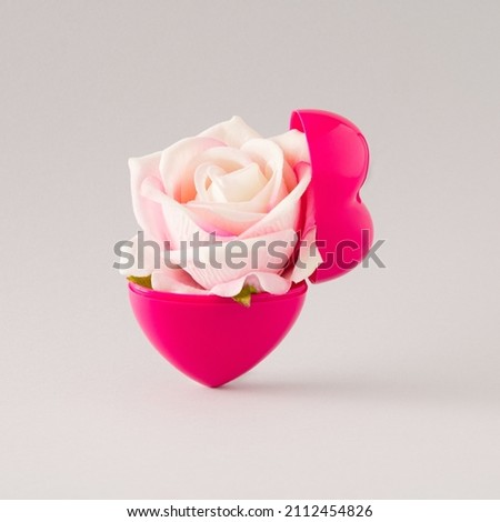 A halved red heart in which a fresh white pink rose blossomed. Minimalist concept of love on gray background
